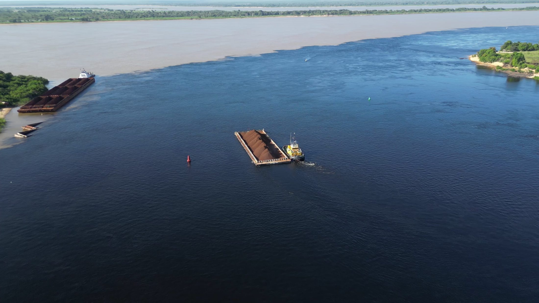 Aerial view of a loaded barge and a tugboat sailing along a river